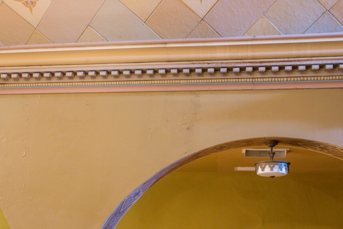 Ornate ceiling molding and an archway with a small security camera fixed above the arch.