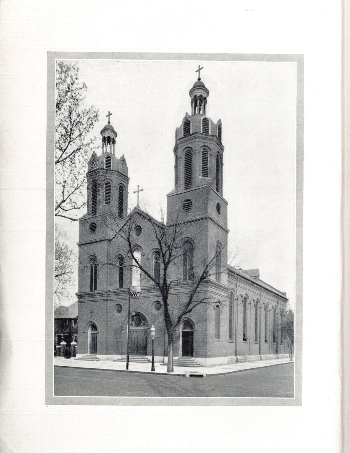 Black and white photo of a church with two tall bell towers, arched windows, and crosses on top.