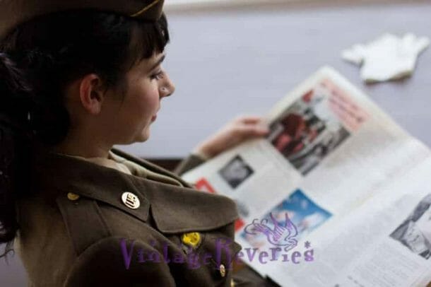 A woman in a WAC uniform reading a newspaper during WWII.