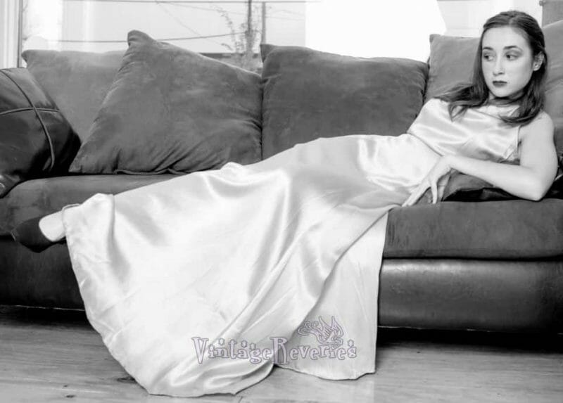 A woman in a satin dress lounging on a couch, reminiscent of 1930s glamour.