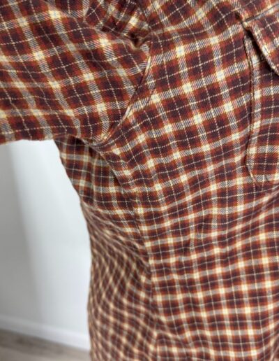Brown plaid flannel Levi's 90s women’s shirt, white buttons, dagger collar, side view, retro grunge style against light background.