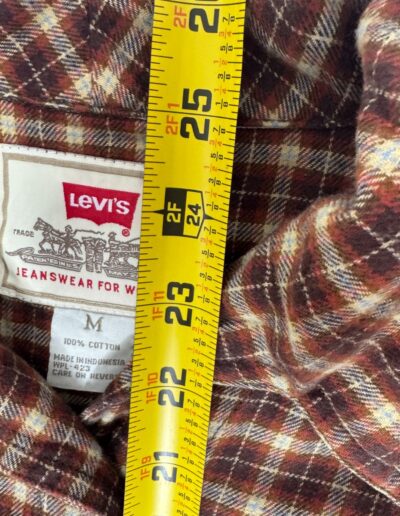 Vintage 90s Levi's red, brown, and white plaid flannel shirt with Levis label, Medium tag, and yellow measuring tape at 23 inches.