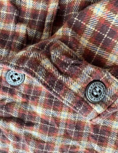 Vintage 90s Levi's women's plaid flannel shirt in brown, red, and yellow with black buttons, dagger collar, soft textured fabric.