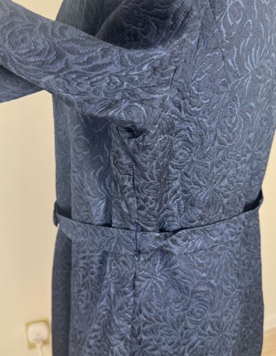 1940s handmade navy blue floral brocade midi dress with mother of pearl buttons, fitted waist, and belt on mannequin.