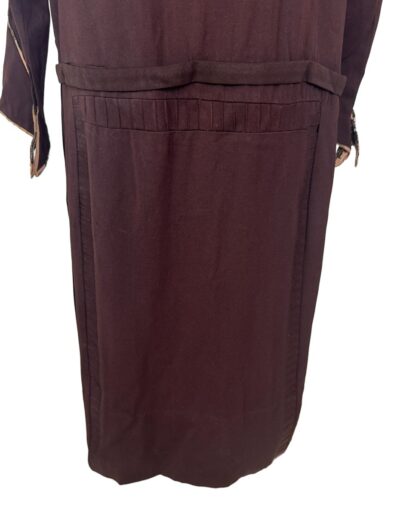 Close-up of a plus size 1920s dark brown Art Deco embroidered drop waist dress with large pocket and cuffed sleeves on white.