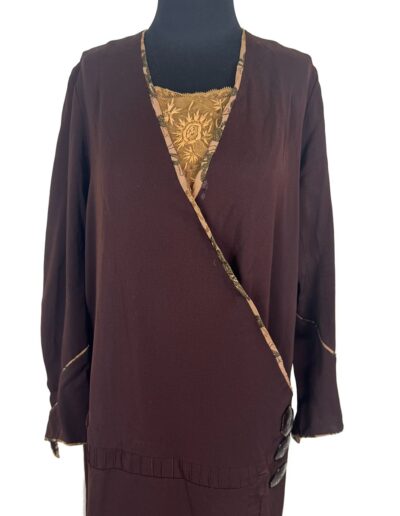 Rare plus size antique 1920s dark brown drop waist dress with Art Deco embroidery, gold floral trim, and side buttons on mannequin.