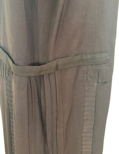 Dark brown fabric of a rare plus size 1920s drop waist dress, with Art Deco embroidery, vertical pocket, and stitched trim.