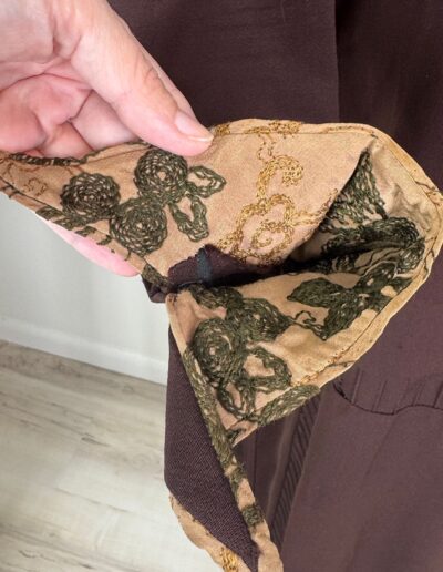 Hand holding Rare Plus Size Antique 1920s Dark Brown Drop Waist Dress with tan green Art Deco floral lining, XL 1X flapper style.
