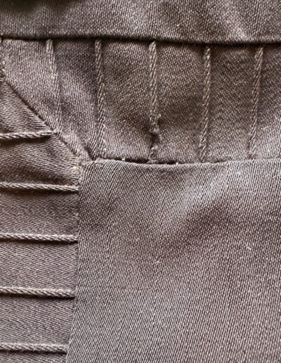 Dark brown fabric seams with parallel vertical stitches, folded sections, and Art Deco embroidery on plus size 1920s flapper dress.