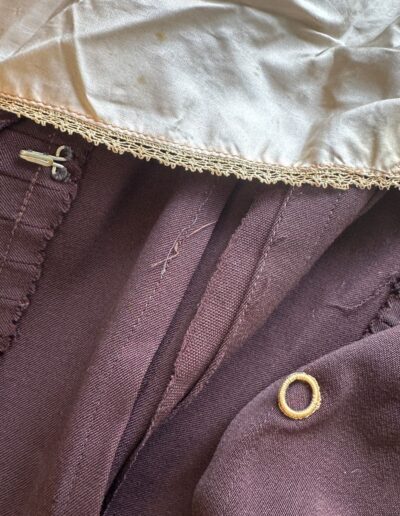 Rare plus size 1920s dark brown drop waist dress interior with cream satin lining, lace trim, and metal ring detail.