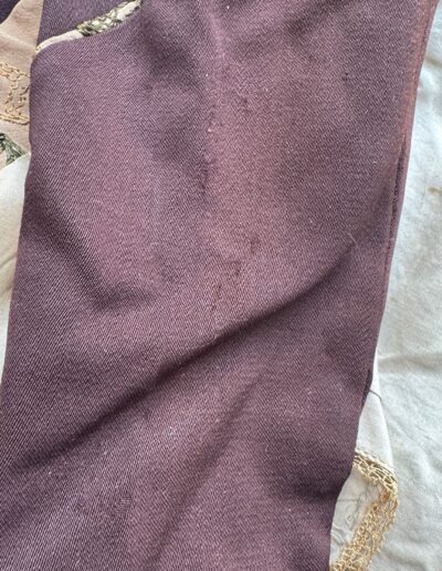 Close-up of plus size 1920s dark brown drop waist dress fabric, purple, cream, gold Art Deco embroidery, XL/1X.