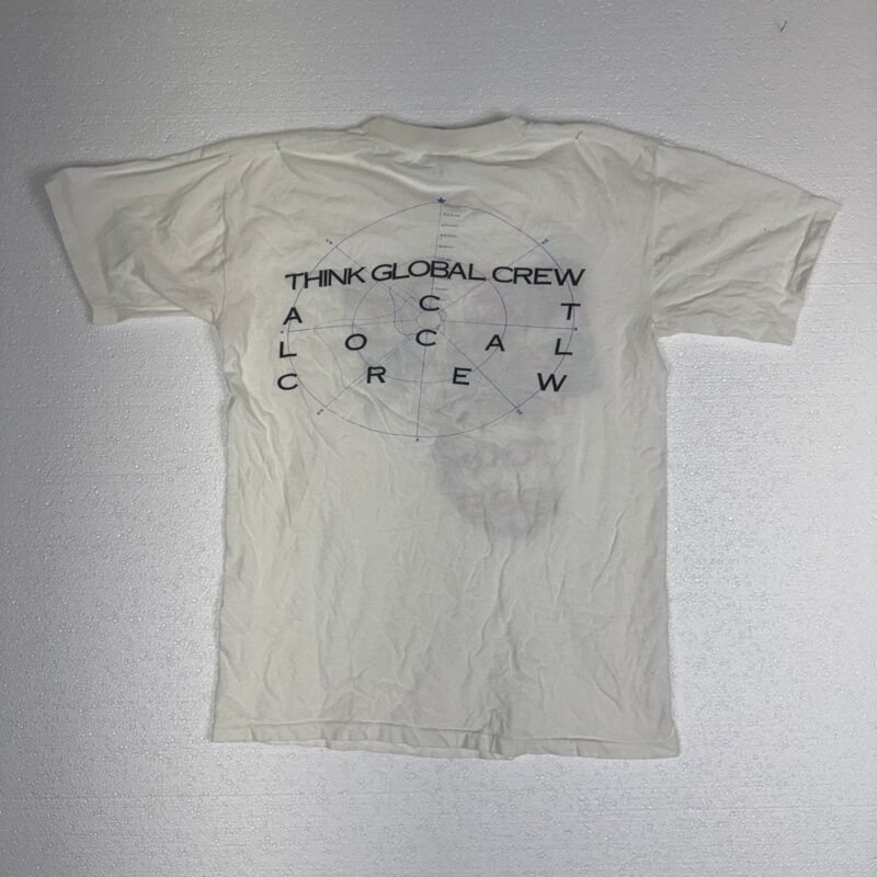 White cotton T-shirt with blue geometric text, THINK GLOBAL CREW ACT LOCAL CREW, in a vintage 1989 R.E.M. concert memorabilia style.