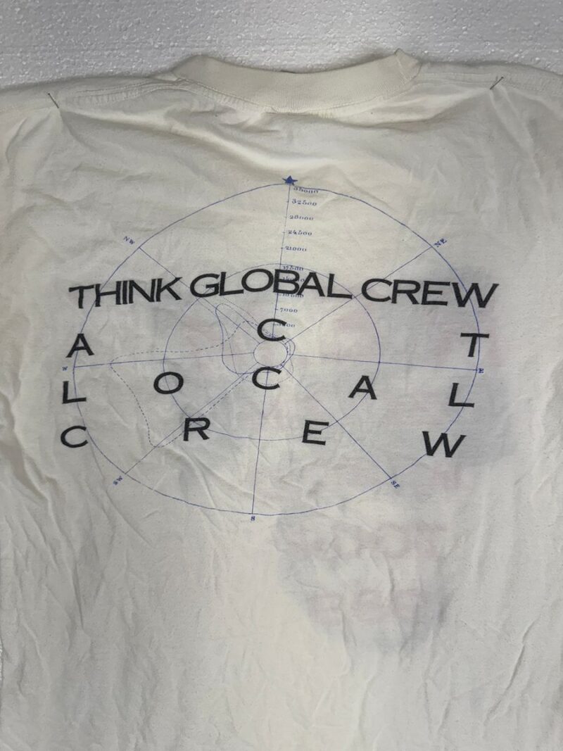 White cotton t-shirt with blue circular graphic, arrows, and vintage R.E.M. Green World Tour Local Crew shirt style text.