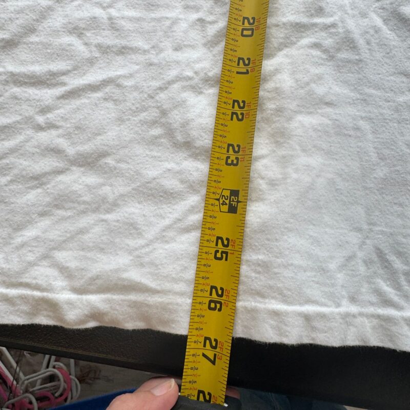 Yellow tape measure showing 25 inches held against a white cotton vintage R.E.M. Green World Tour T-shirt.