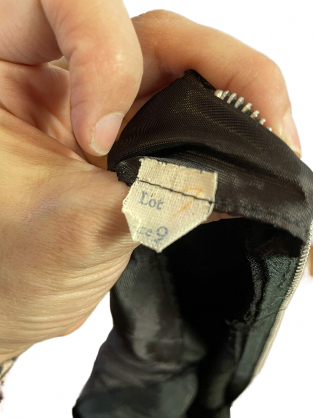 A person is holding a Sexy little black dress vintage 1950s sheath with a label.