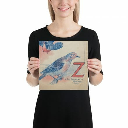 A woman is holding up a poster with an image of a Z is for Zenaidura bird and the letter Z.